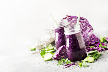 Healthy vegan detox purple smoothies or juice from red cabbage, cucumbers with chia seeds in glass bottles on  gray background, selective focus