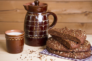 Rye bread with milk in a glass and jug on a wooden background