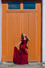 Fototapeta premium Beautiful young woman in a long red evening gown with a train