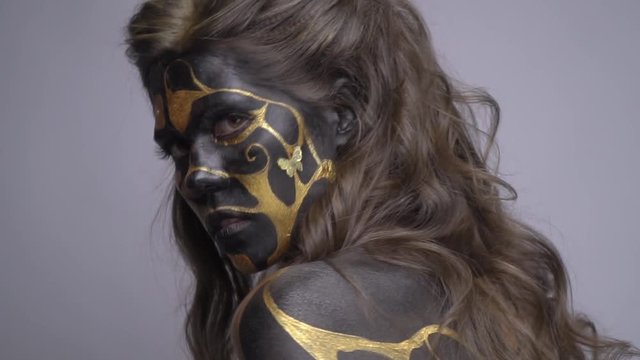 A secular model in a black ash make-up poses in a judiciary and looks around at the camera, slow motion