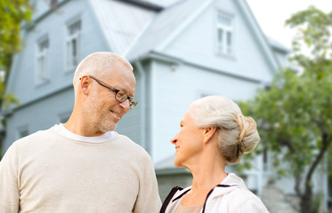 old age, accommodation and real estate concept - happy senior couple over living house background