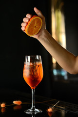 orange cocktail with ice and orange in a glass on a black table