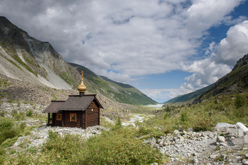 The chapel is high in the Altai mountains at the foot of the Belukha mountain. Snowy mountains and an Orthodox church.
