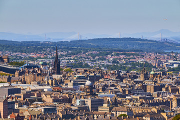 Edinburgh cityscape with churches, Forth bridge and Queensferry Bridge in the background.