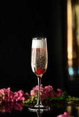 Champagne in a glass with a red berry on a black table