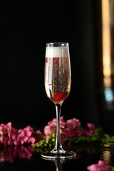 Champagne in a glass with a red berry on a black table