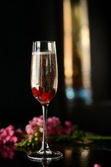 Champagne in a glass with a red berry on a black table