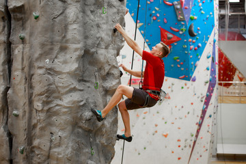 Photo from side of sports man exercising on climbing wall - Powered by Adobe