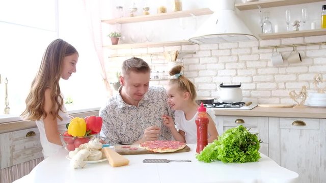 Father and daughters having a fun in the kitchen and making pizza
