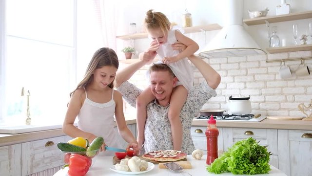 Father and daughters having a fun in the kitchen and making pizza