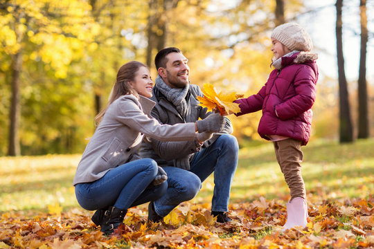 family, season and people concept - happy mother, father and little daughter with maple leaves at autumn park