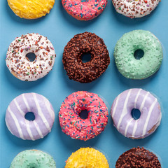 Pastel blue background filled with colorful donuts