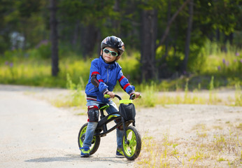 Fototapeta premium Happy boy having fun riding a bicycle with glasses, helmet, in defense