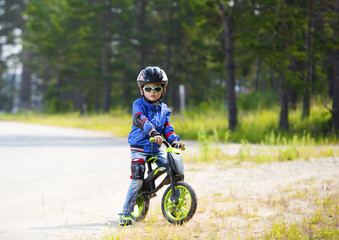 Naklejka premium Happy boy having fun riding a bicycle with glasses, helmet, in defense
