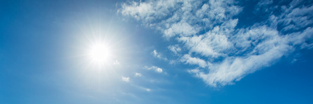 Shining sun on blue sky with small clouds banner background.