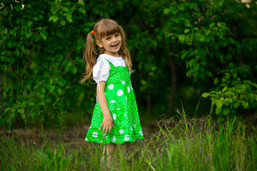 Little girl walk in green garden in sunny summer day