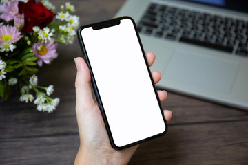female hand holding phone isolated screen over desk with laptop