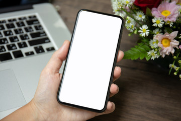 female hand holding phone isolated screen over desk with laptop