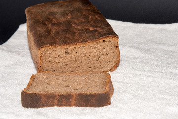 Black rye bread sliced on white material. Freshly baked homemade rye and white flour bread. Close up. Copy space.