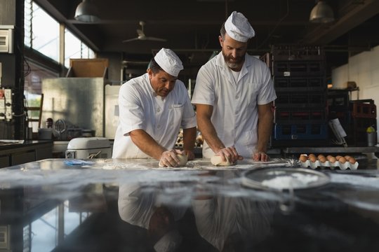 Male baker preparing dough with his coworker