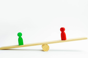 wooden figures of people. rivals in business stand on the scales. trial. conflict. victory and...