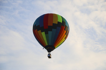 colorful hot air balloon against blue sky. hot air balloon is flying in white clouds. beautiful...