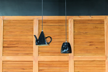 kitchen interior decoration. Lanterns in shape of kettle and cup on wooden panel wall background