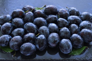 Ripe juicy plums on slate board