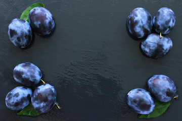 Ripe fresh plums on slate board with space for text