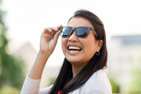 summer, eyewear and people concept - portrait of happy smiling young woman in sunglasses outdoors