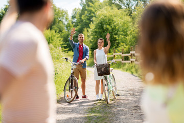 people, leisure and lifestyle concept - happy young friends with fixed gear bicycles in summer waving hands