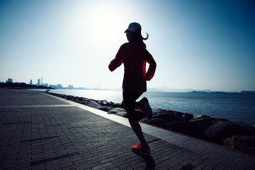 sporty young fitness woman running on sunrise seaside