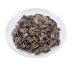sunflower seeds pile against in white plate  isolated on white background