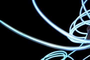 Semi-transparent five millimeters, light glowing wire electro-luminescent cable with neon, white neon light and color on a black background