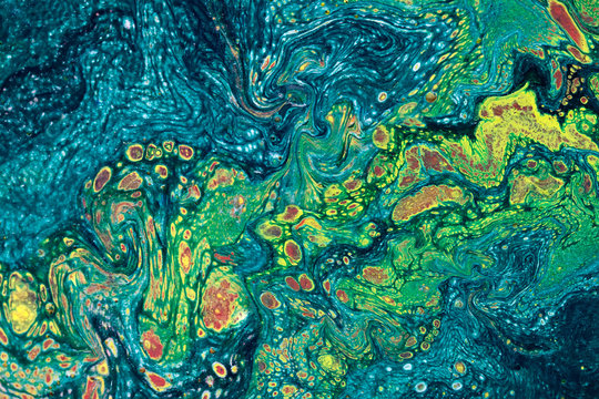 Marbling textured creative background. Mixing green, blue, yellow and red paints. Lines and bubbles.  Liquid paint.