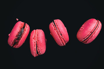 Pink macarons with cranberry flavor, on a black background.