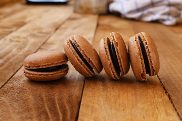 Chocolate macarons on a wooden table, with a vintage style.