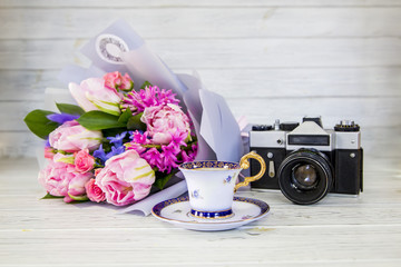 tender pink bouquet, antique camera and a cup of coffee on a light background