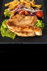 Juicy grilled chicken breast steak with fresh vegetables and french fries