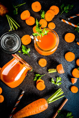 Fresh carrot juice or smoothie with carrots on dark blue background, above copy space