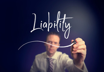 A businessman writing a liability concept with a white pen on a clear screen.
