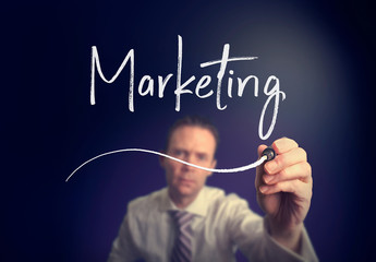 A businessman writing a marketing concept with a white pen on a clear screen.
