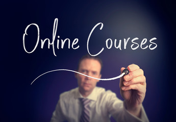 A businessman writing a online courses concept with a white pen on a clear screen.