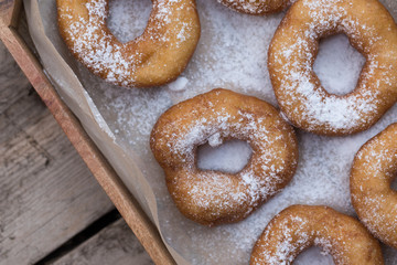 Homemade donuts with icing sugar powder on a wooden background