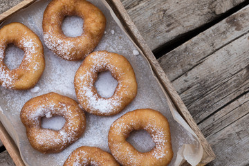 Homemade donuts with icing sugar powder on a wooden background