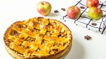 Traditional American apple pie with dough decoration in a grid on a white table. Autumn baking...