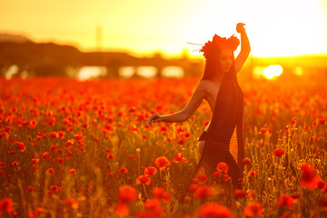 beautiful woman in poppy field at sunset