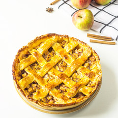 Traditional American apple pie with dough decoration in a grid on a white table. Autumn baking...