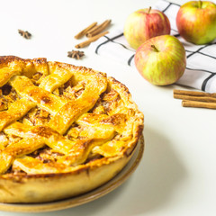 Traditional American apple pie with dough decoration in a grid on a white table. Autumn baking...