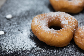 Homemade donuts with icing sugar powder on a wooden background